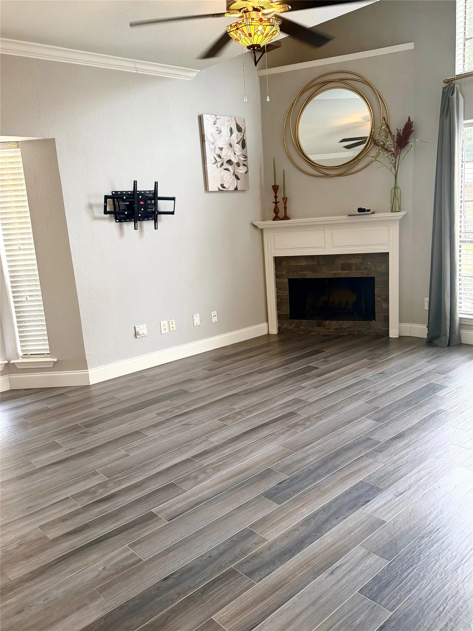 Vaulted ceiling, crown molding, wood-finish flooring, built-in fireplace, and a ceiling fan with integrated lighting