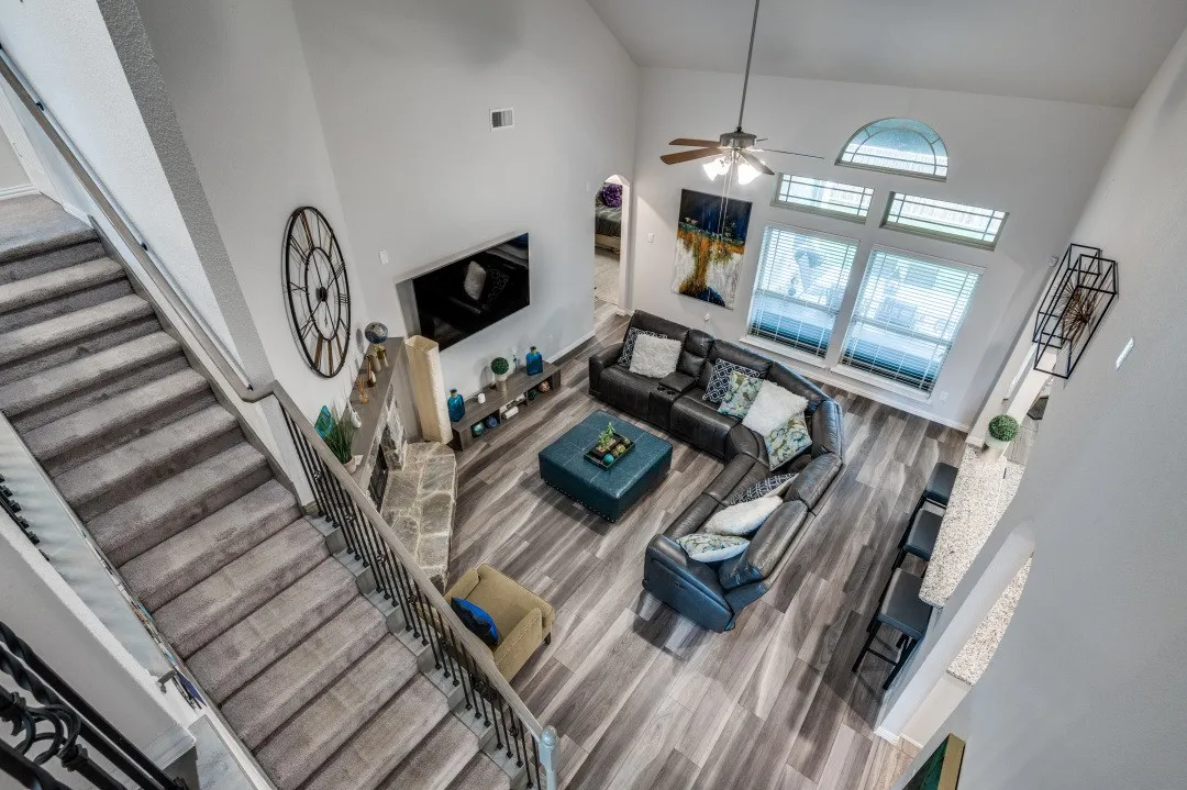 Two-story living area featuring vaulted ceilings, wood-finish flooring, a stone-faced fireplace
