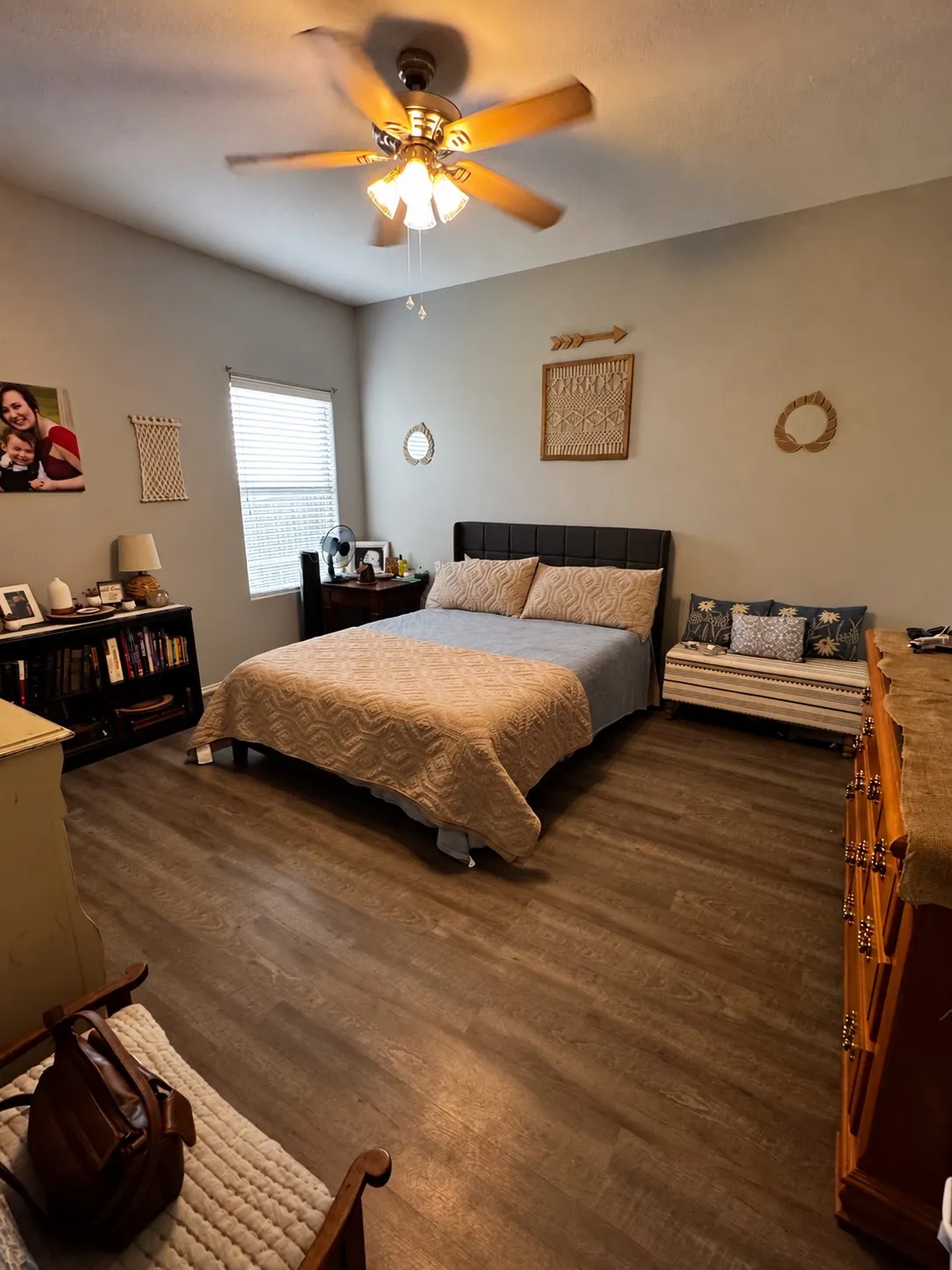 Wood-finish flooring, ceiling fan with integrated lighting, window with blinds, and built-in shelving