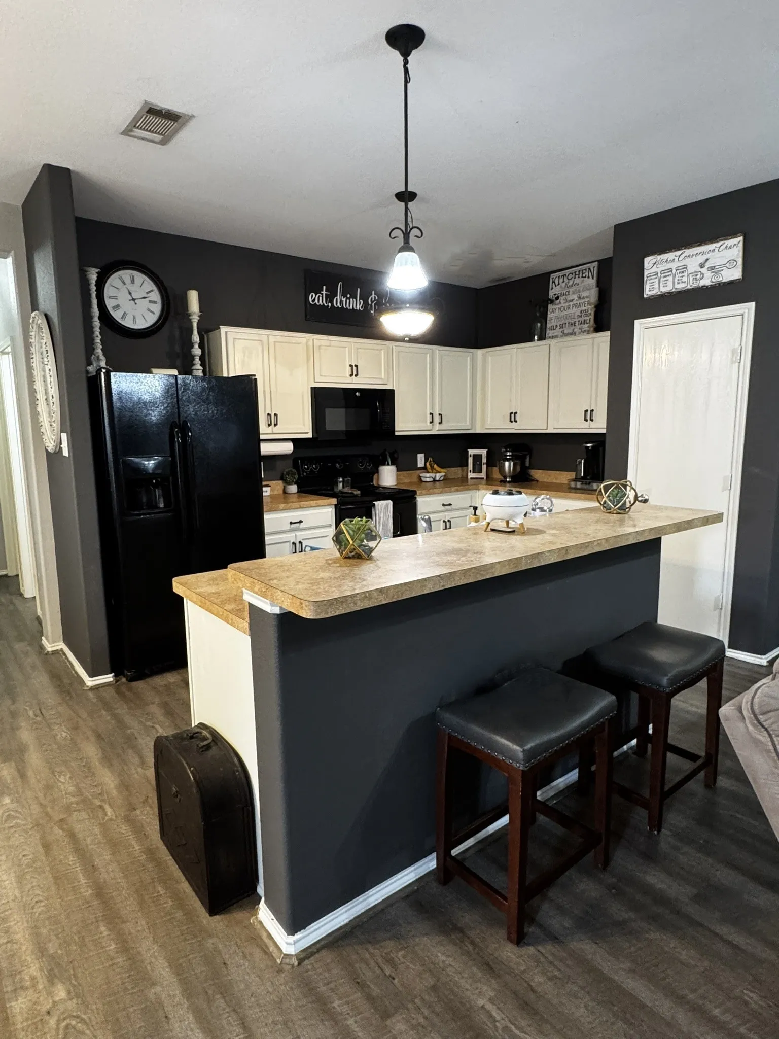 Kitchen featuring wood-finish flooring, cream cabinetry, dark countertops, and a peninsula island with seating