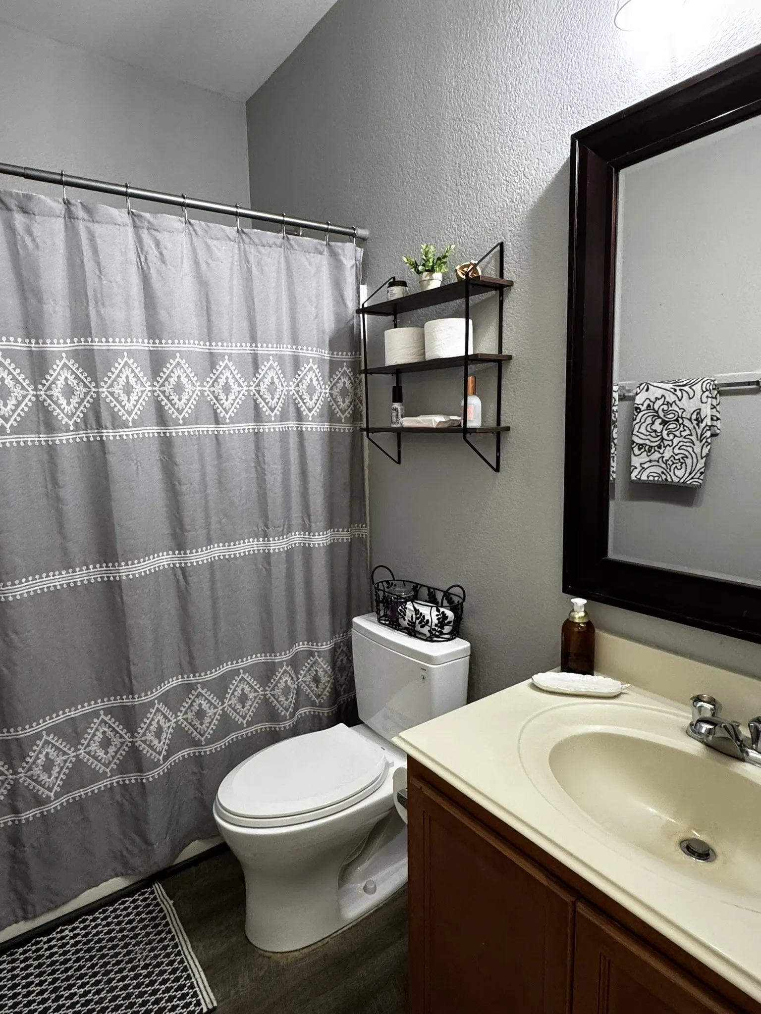 Bathroom featuring a built-in vanity with an integrated sink, a large framed mirror, and wood-finish flooring