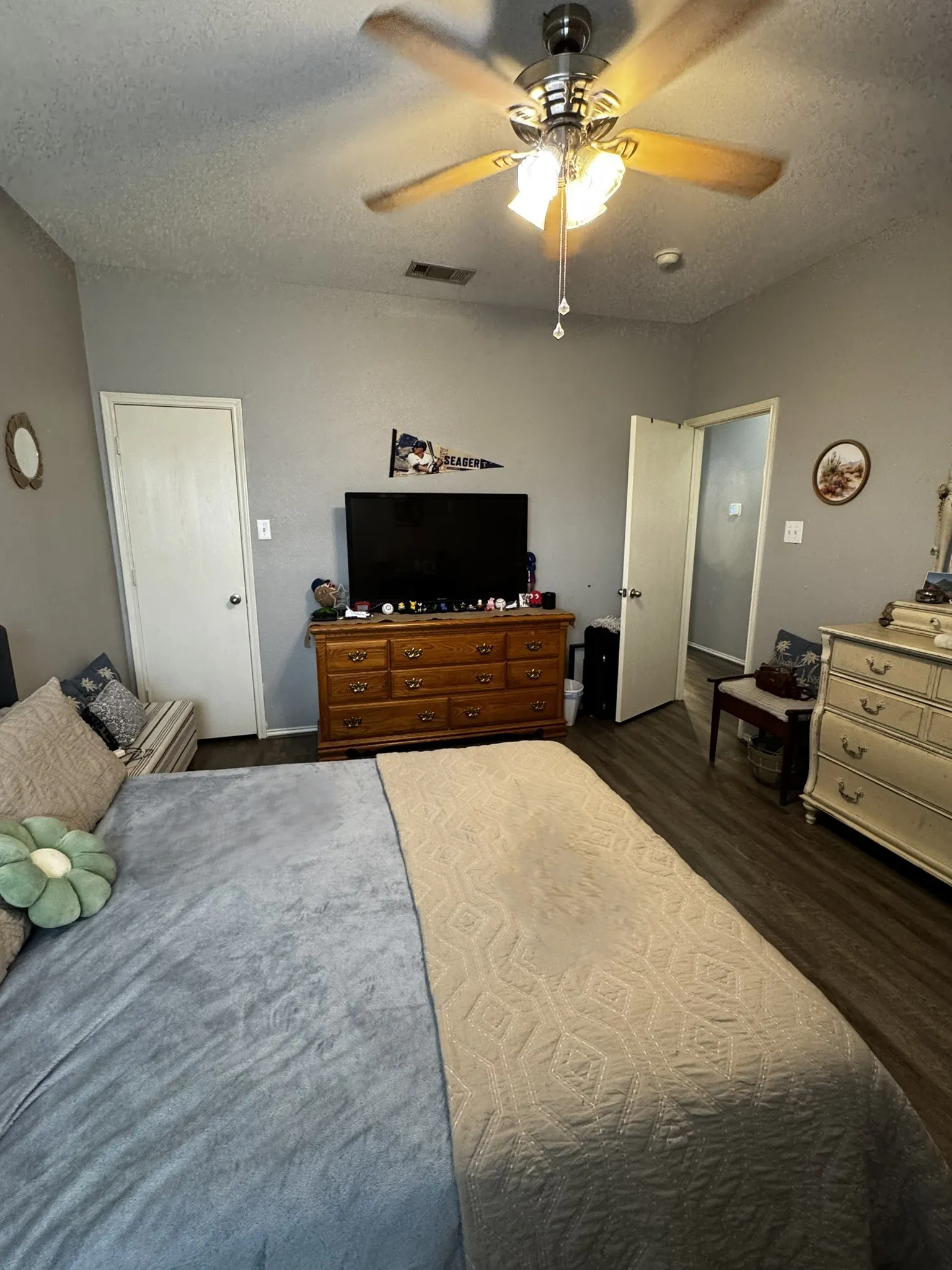 Spacious bedroom featuring wood-finish flooring, ceiling fan with integrated lighting, and dual closets