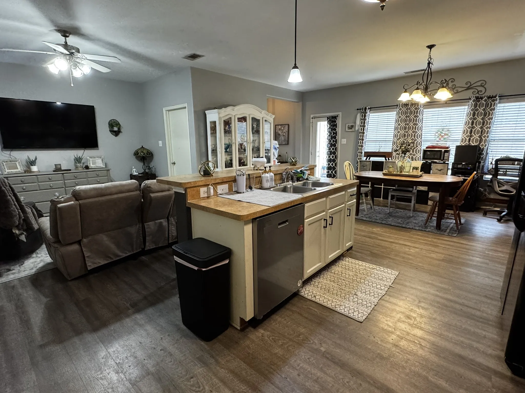 Open concept living area with wood-finish flooring, kitchen island with integrated sink, recessed lighting, and a ceiling fan