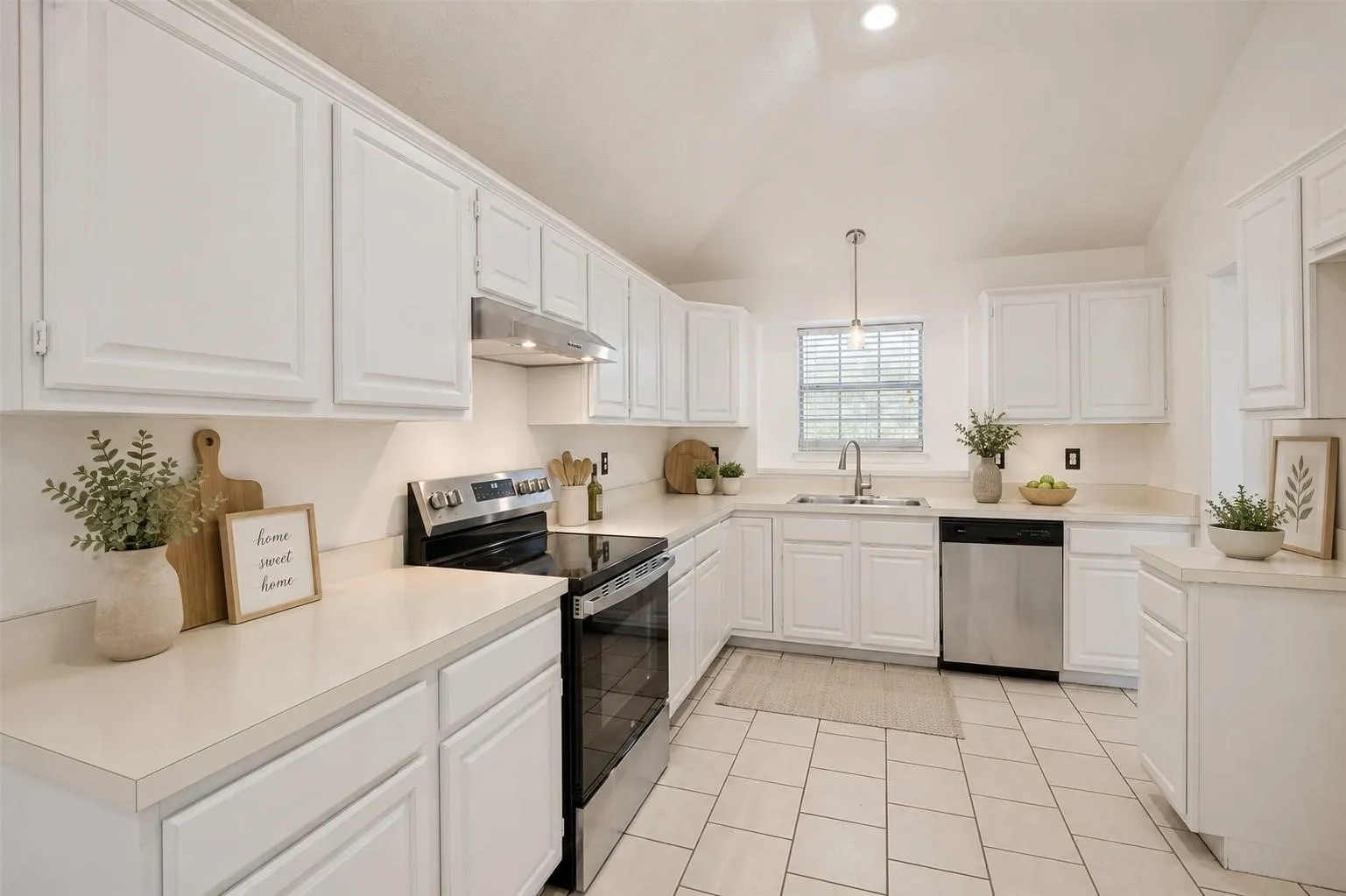 Bright kitchen featuring extensive white cabinetry, light countertops, stainless steel appliances, and tile flooring