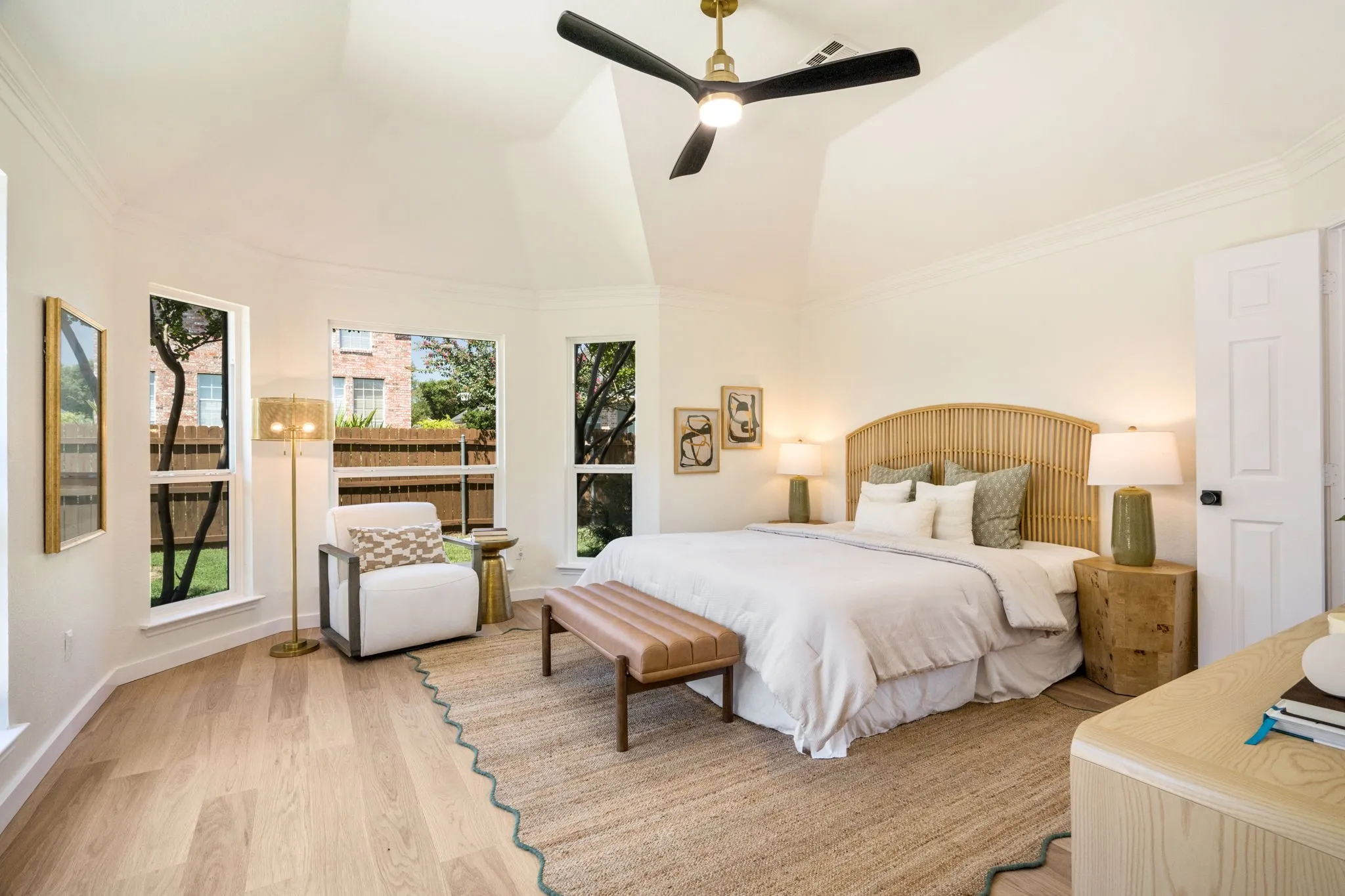 Vaulted ceiling with a contemporary ceiling fan, wood-finish flooring, multiple windows, and a panel door