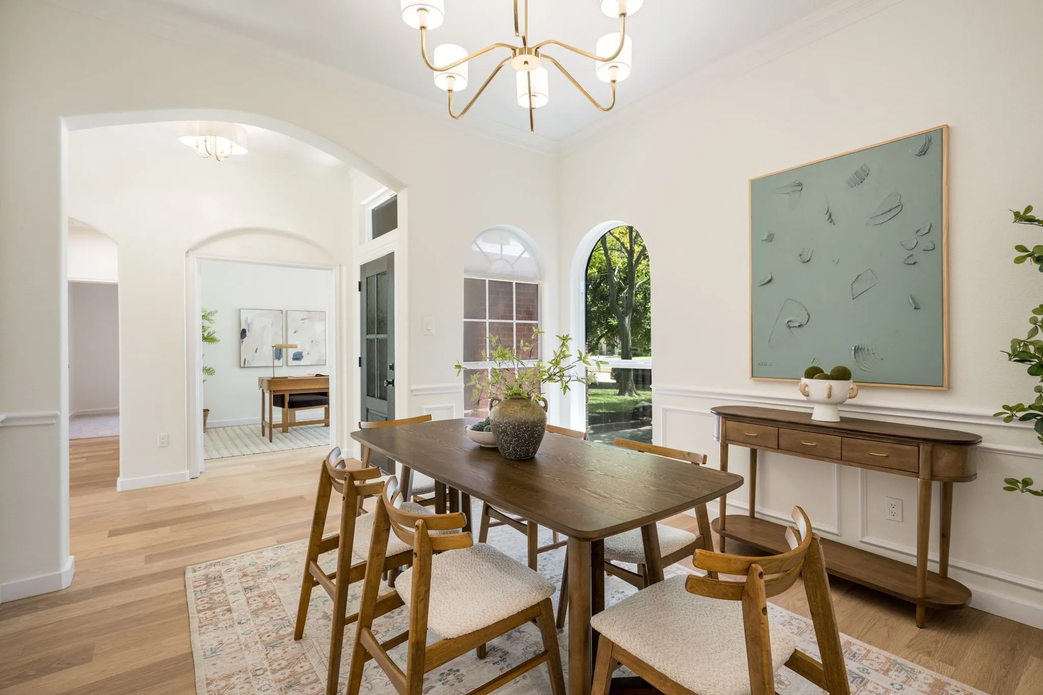 Arched doorways, wainscoting, wood-finish flooring, and a contemporary chandelier