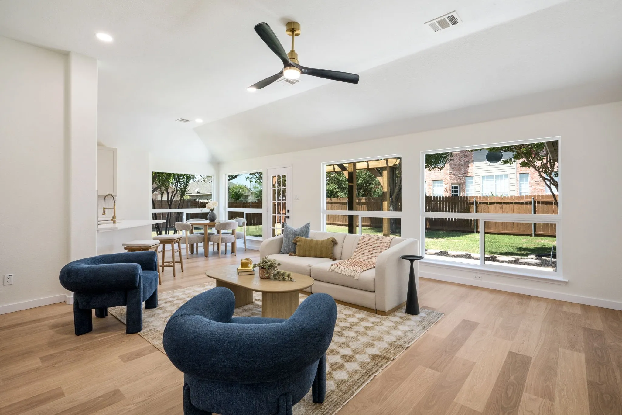 Vaulted ceiling with a contemporary ceiling fan, recessed lighting, wood-finish flooring, and expansive windows