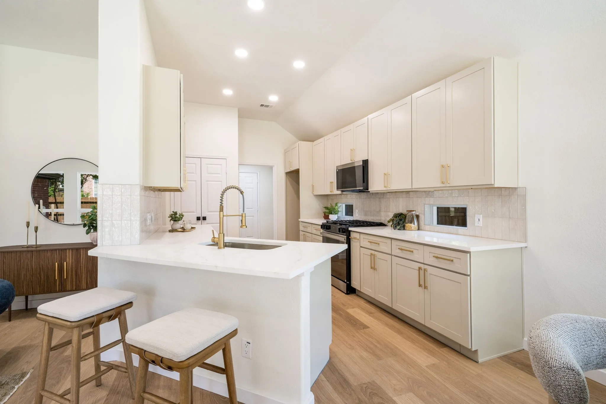 Kitchen featuring an island with a sink, white countertops, extensive cabinetry, light-toned wood-finish flooring, and recessed lighting