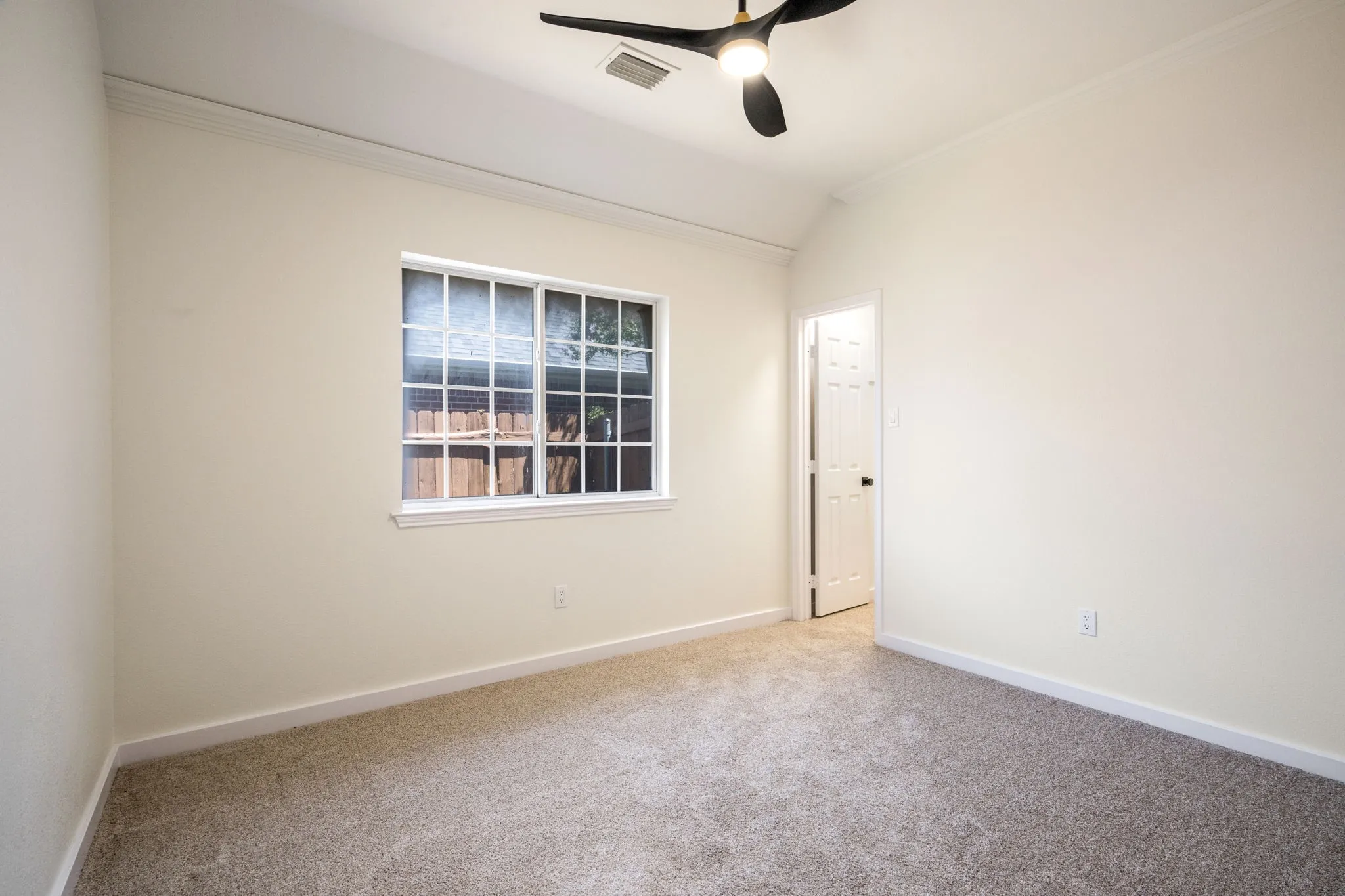Plush carpet flooring, a multi-pane window, and a modern ceiling fan with integrated lighting