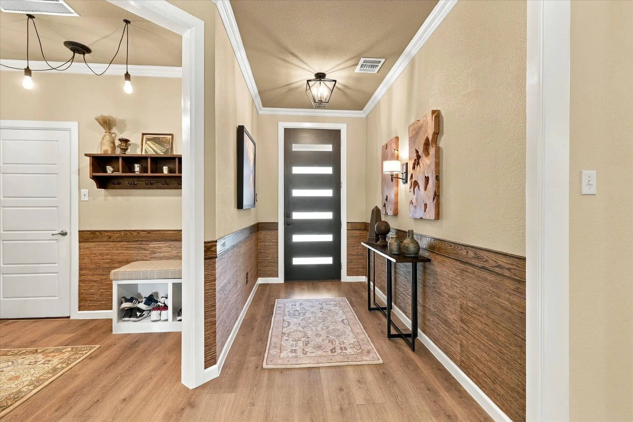 Step inside to a warm, designer-inspired entry where rich wood accents, grasscloth wallpaper, crown molding and statement lighting create an immediate sense of character.