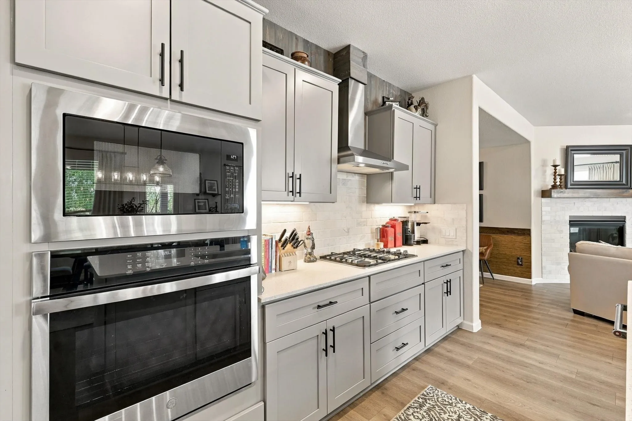 Designer details elevate the kitchen with abundant cabinetry, under-cabinet lighting, a striking backsplash, gas cooking and a dramatic custom-look range hood.