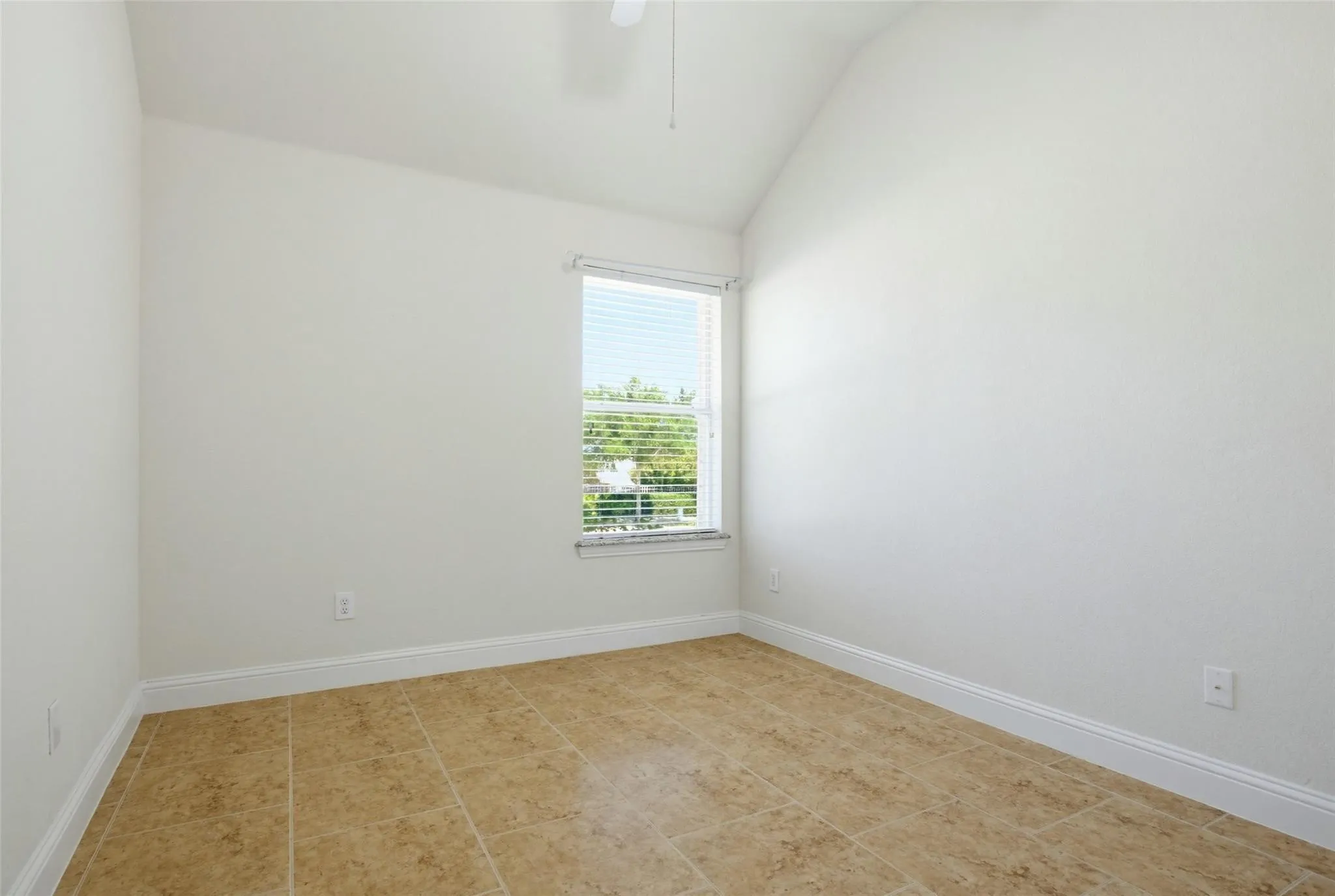 Vaulted ceiling, ceiling fan, single window with blinds, tile flooring, and white trim