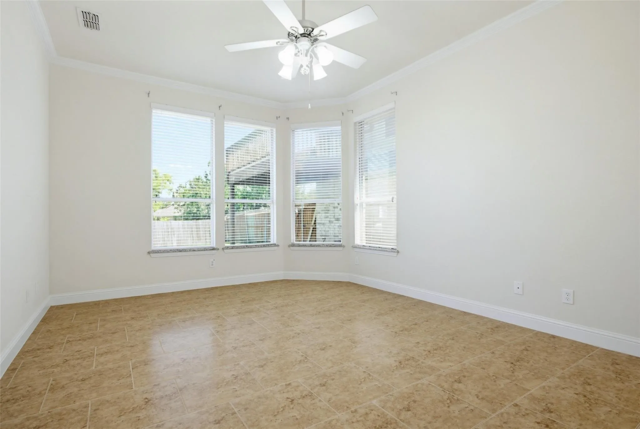 Bay window with multiple large windows, ceiling fan with integrated lighting, crown molding, and tile flooring