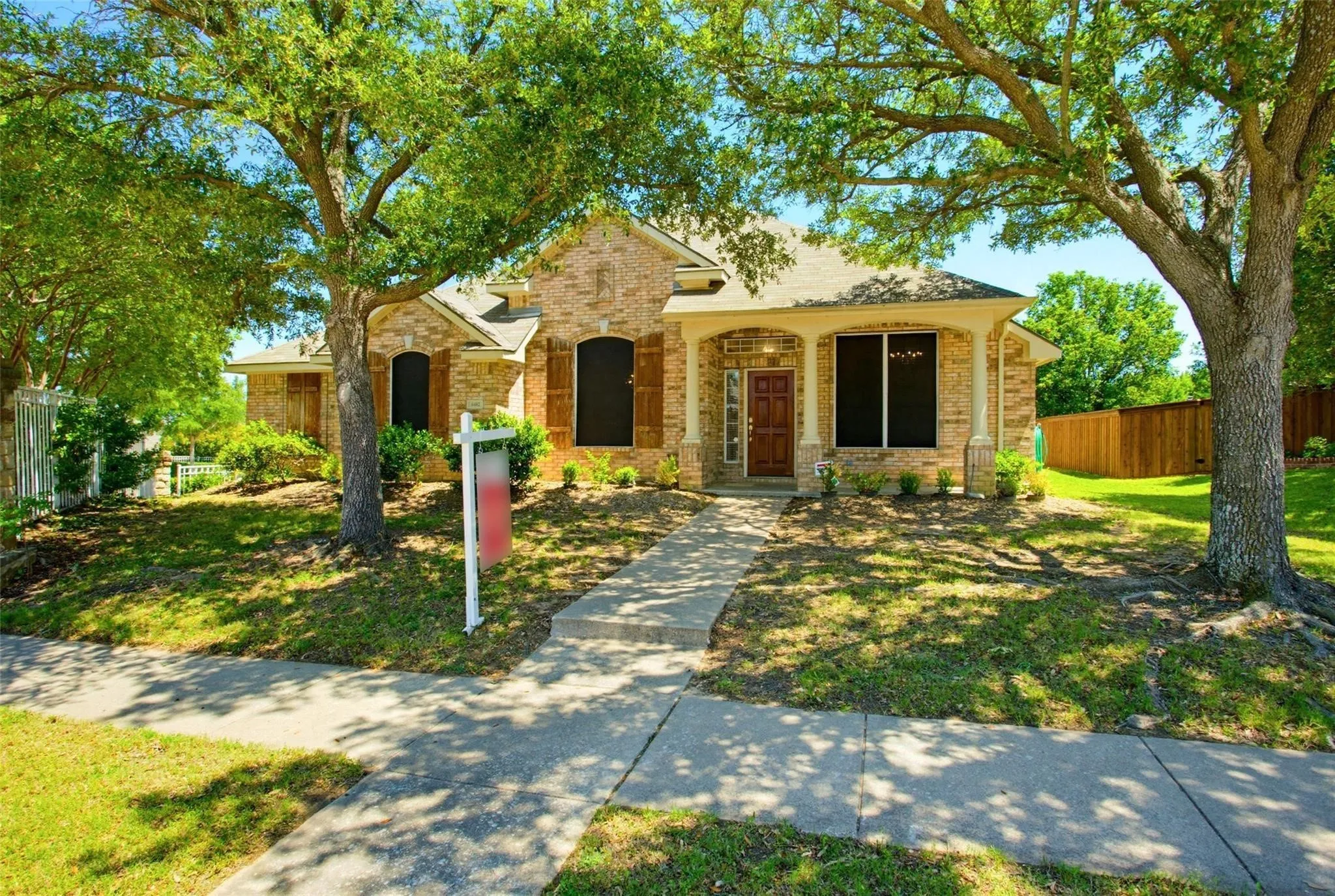 Brick exterior with arched entry, covered front porch with columns, and a concrete walkway