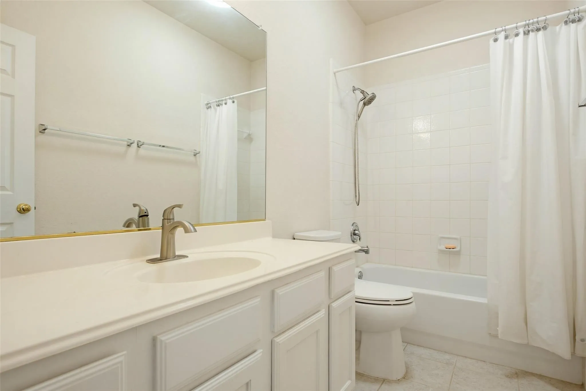 White vanity with an integrated sink, brushed nickel faucet, and a tub-shower combination with white subway tile surround
