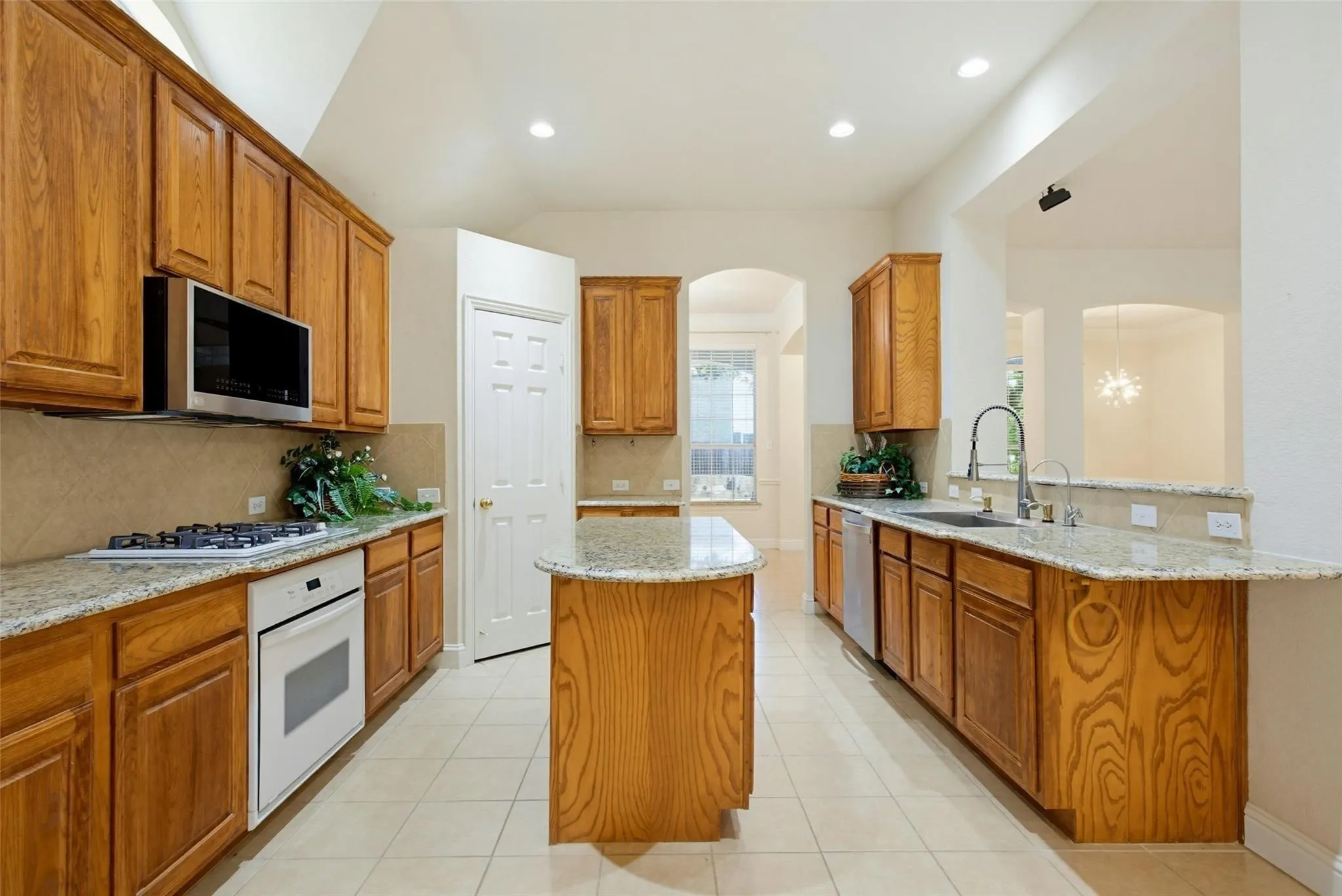 Kitchen featuring wood cabinetry, light-toned countertops, tile flooring, and integrated appliances
