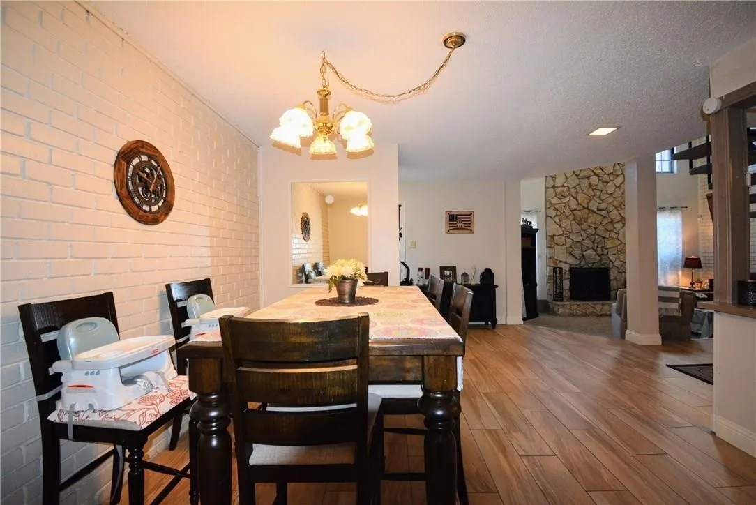 Wood-finish flooring throughout, with a stone-clad fireplace and white brick accent walls
