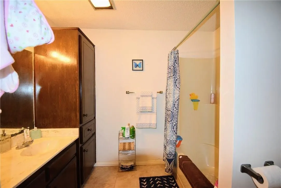 Vanity with integrated sink, wood-finish cabinetry, and a shower/tub combination