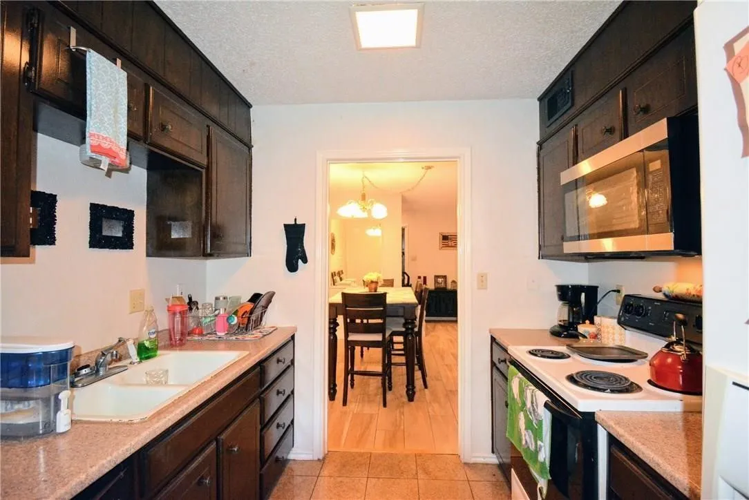 Dark wood-finish cabinetry, built-in microwave, and a white electric range