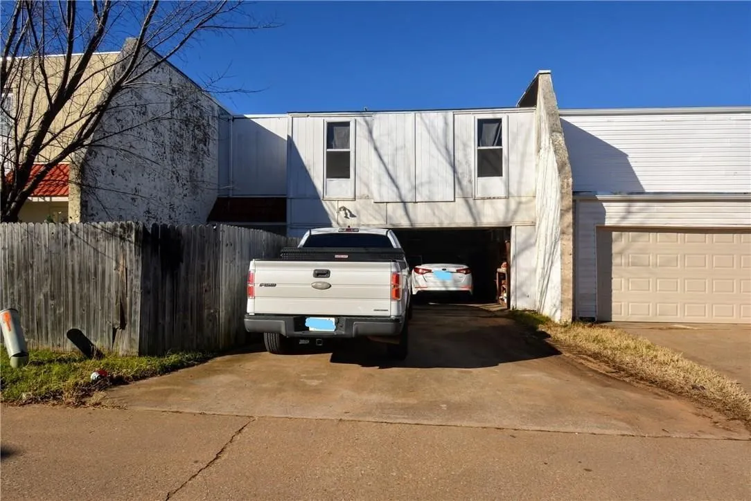 Driveway entry with an attached garage featuring a paneled door, and an additional carport