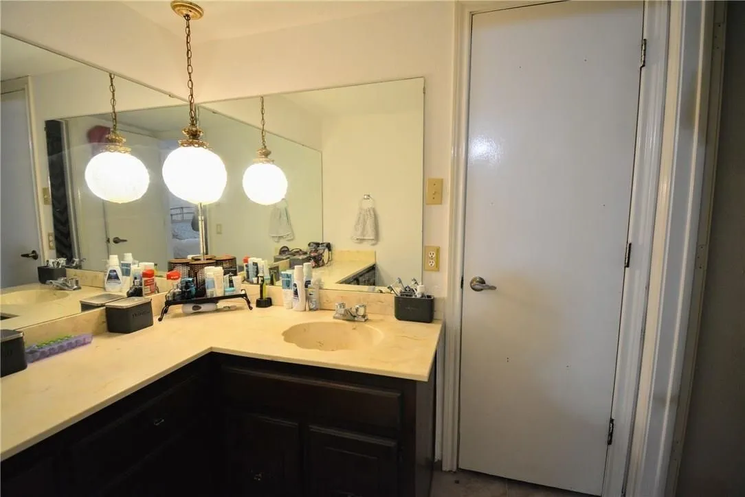 Expansive wall-mounted mirror over a vanity with a light-toned countertop, integrated sink, and dark wood-finish cabinetry