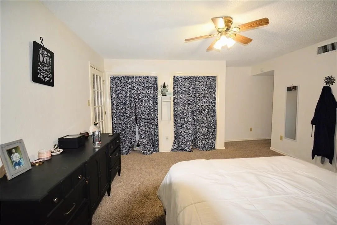 Ceiling fan with light fixture, carpeted flooring, white wall paint, and double French doors with interior lites
