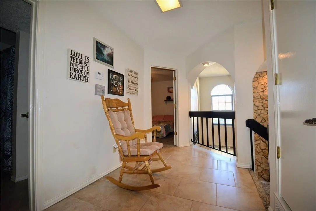 Tiled flooring, arched doorways, a stone-accented wall, and dark metal railing