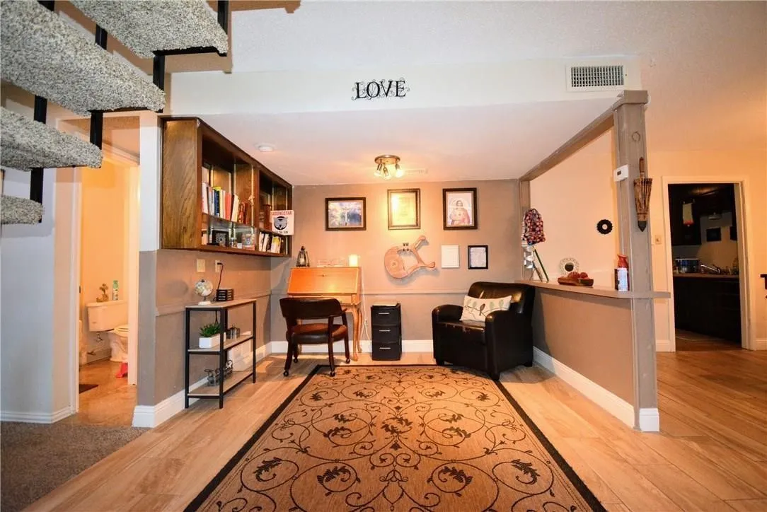 Wood-finish flooring with a carpeted area, built-in shelving, and a spiral staircase