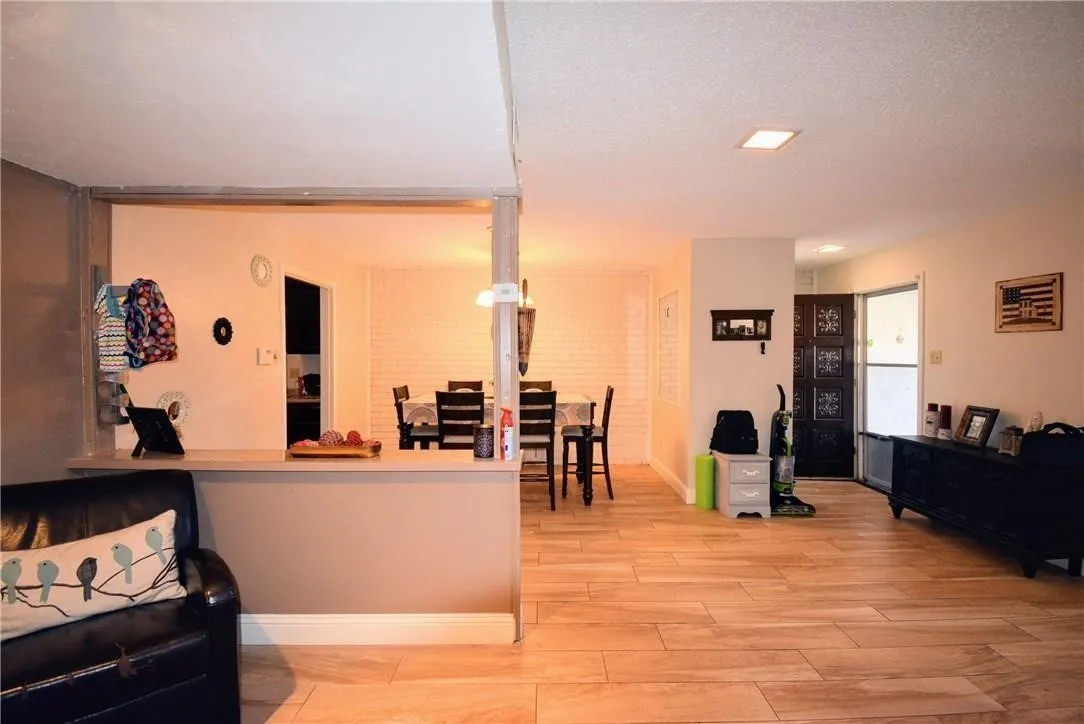 Wood-finish flooring throughout, recessed lighting, and a partial wall separating living spaces
