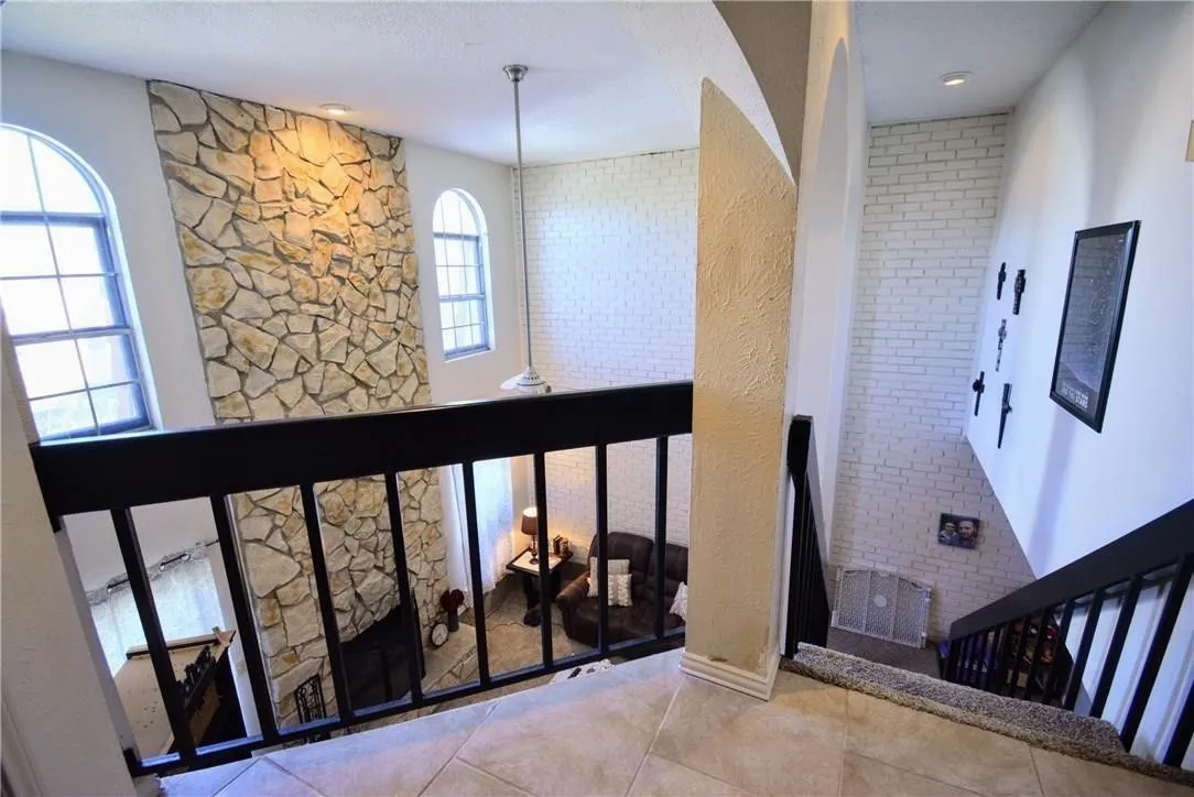 Soaring ceilings with stone accent wall, arched windows, and white brick detailing