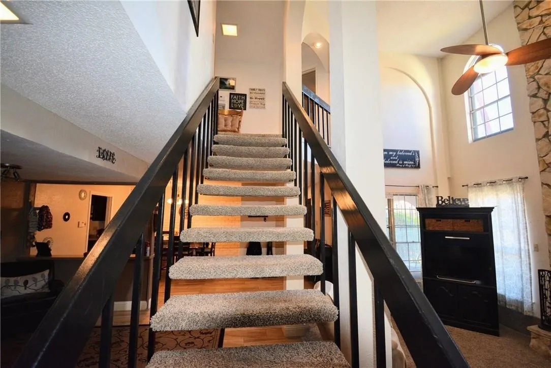 Carpeted staircase with wood-finish risers and black railings