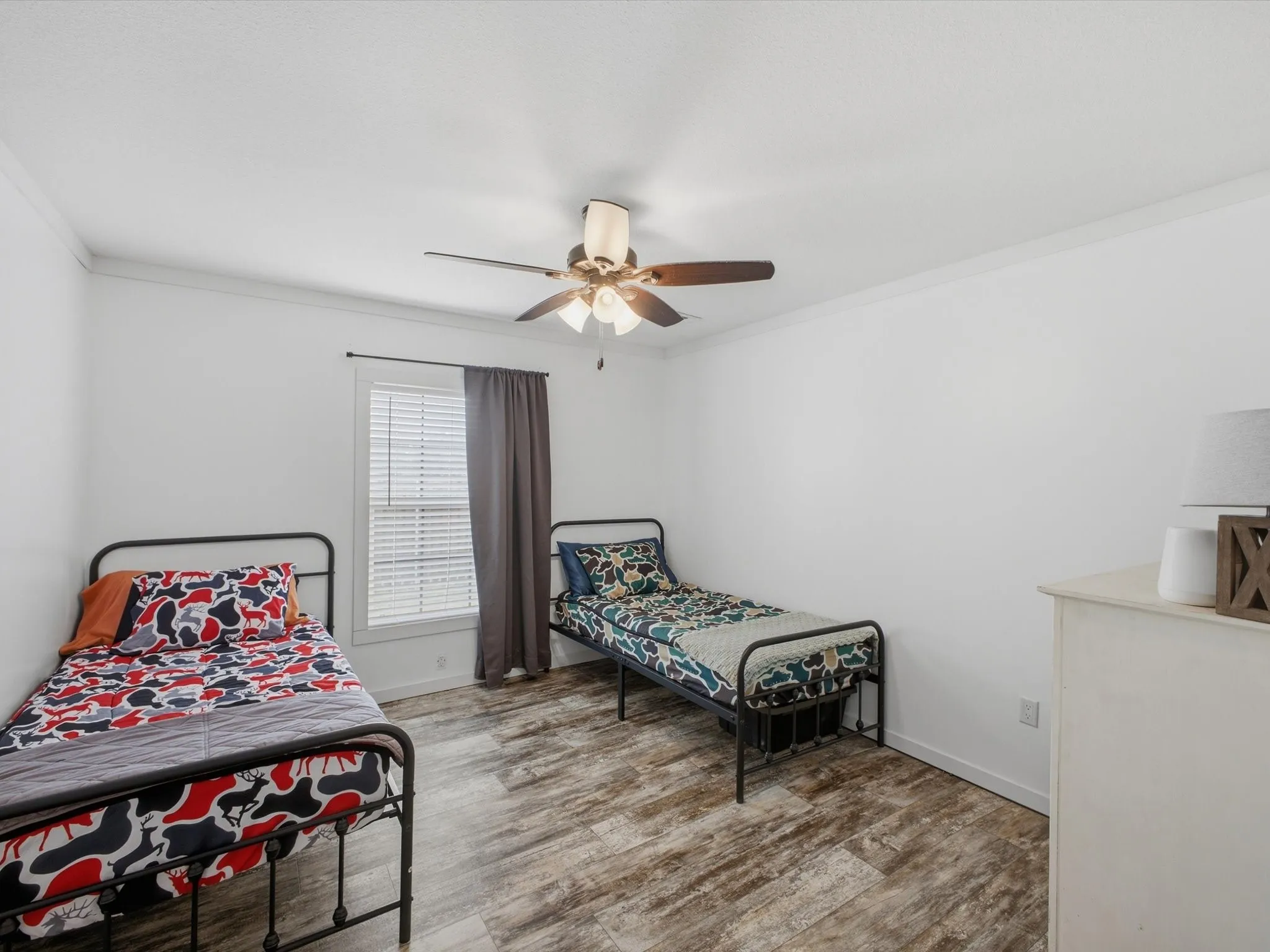 Room featuring wood-finish flooring, a window with blinds, a ceiling fan with integrated lighting, and crown molding
