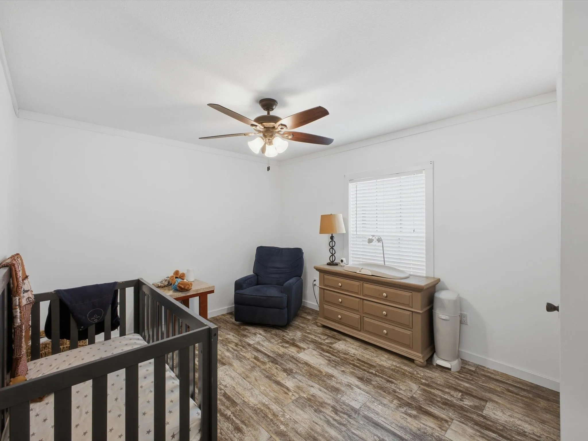 Wood-finish flooring with white walls and a ceiling fan