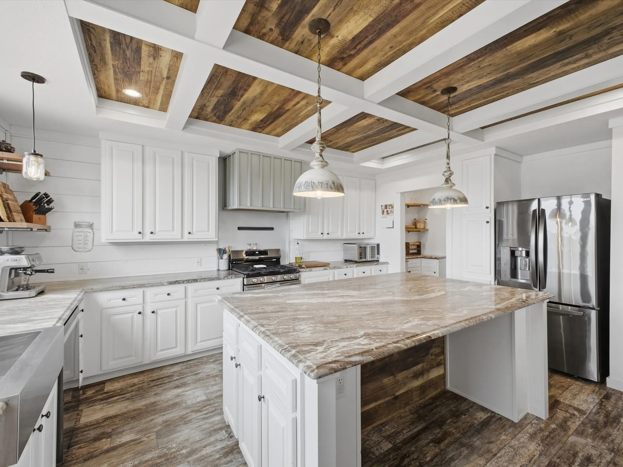 Chef's kitchen featuring white shaker cabinetry, stainless steel appliances, and a large center island with wood-finish countertop