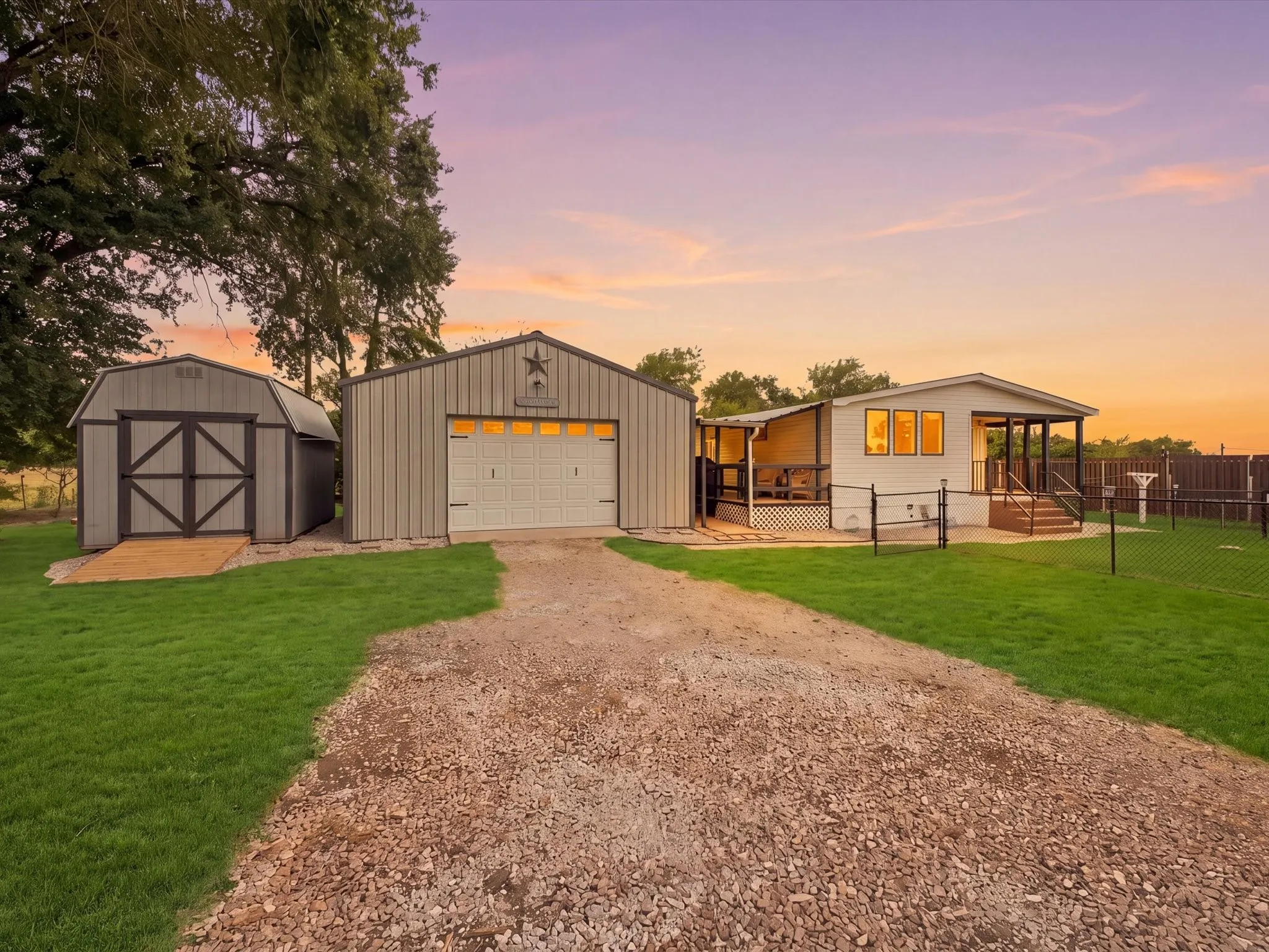 Property featuring a gravel driveway, detached metal garage, separate storage shed, and a covered front porch with steps