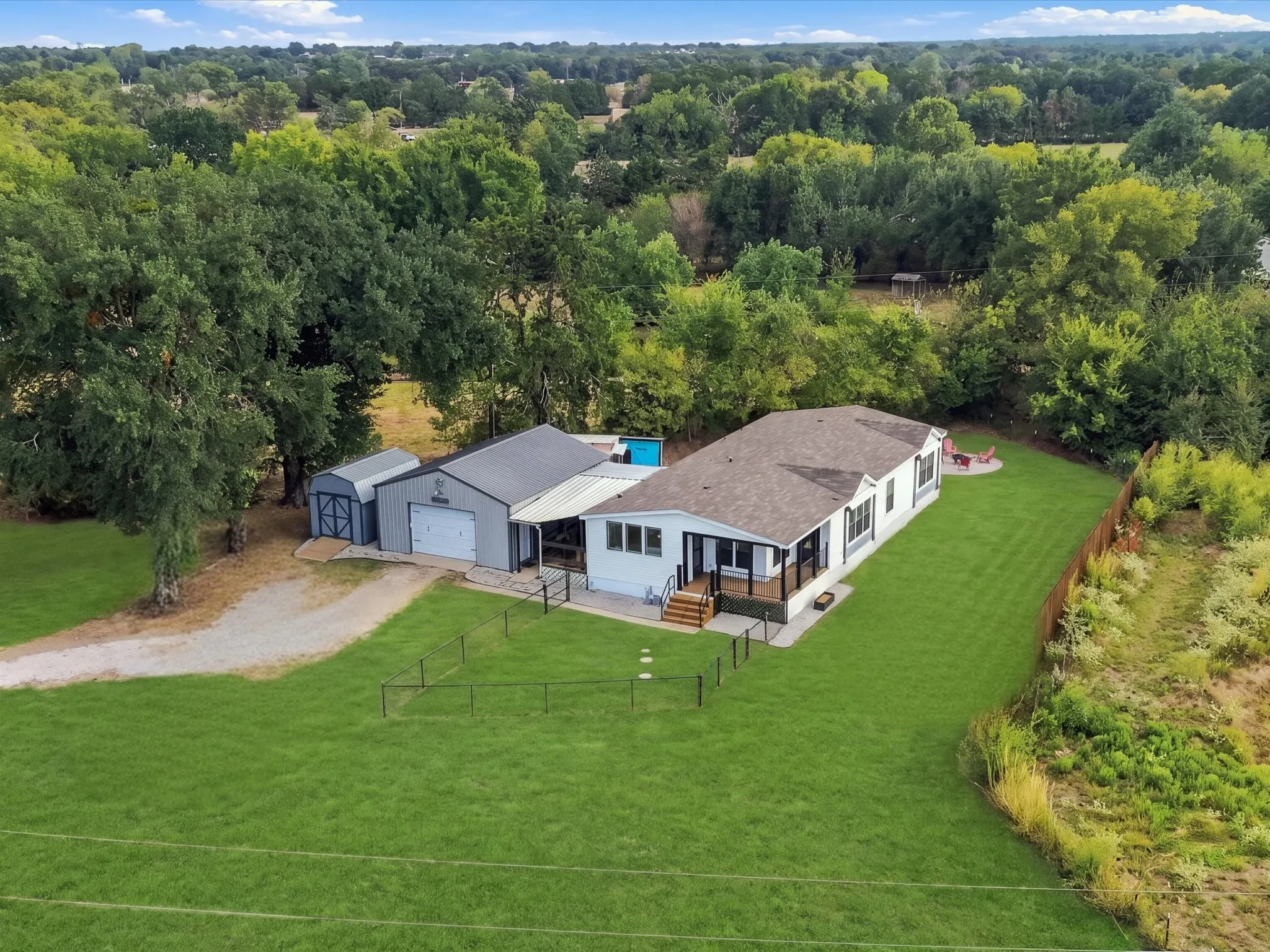 Expansive green lawn surrounding a single-story residence with a covered porch
