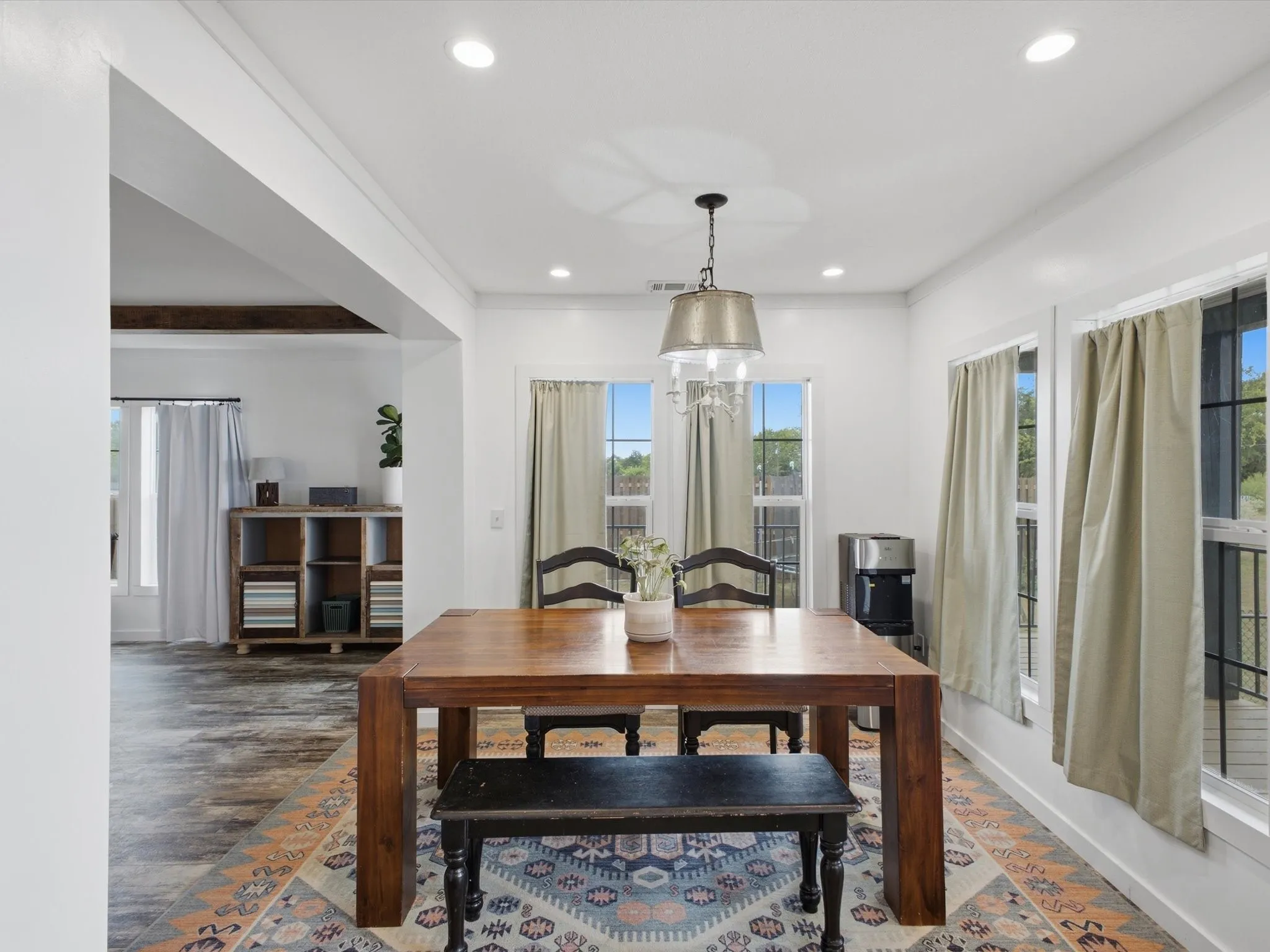 Recessed ceiling lighting, decorative chandelier, wood-finish flooring, white trim, and multiple windows