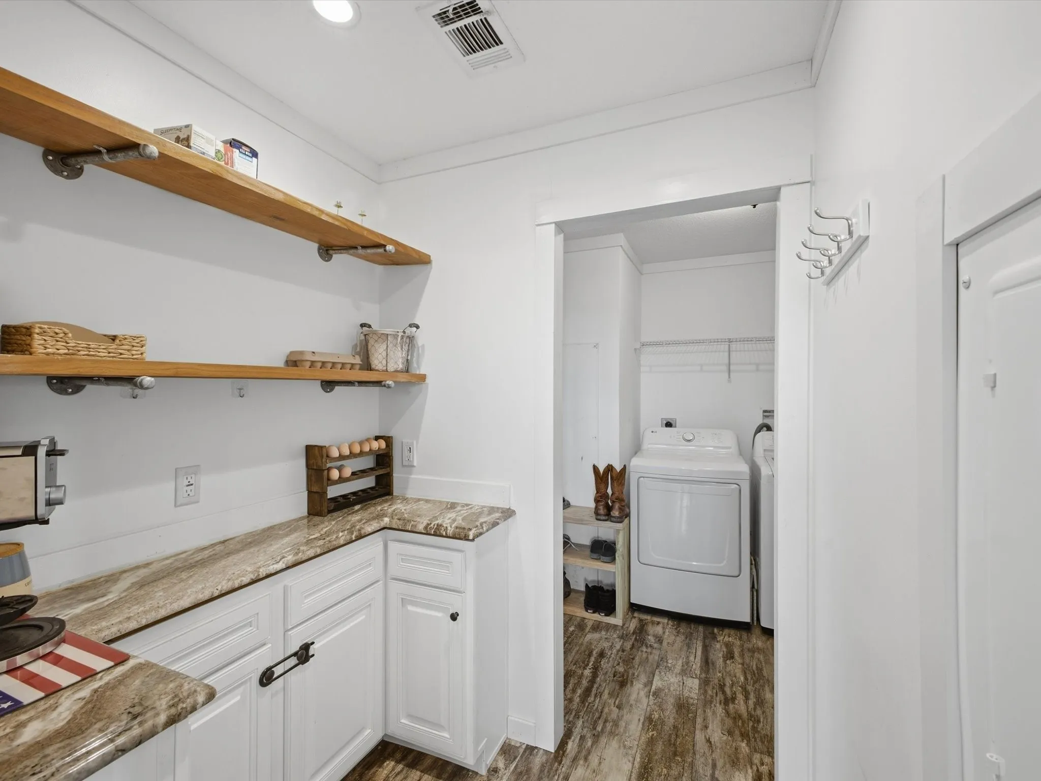 White cabinetry with a natural stone-finish countertop, open wood shelving, and wood-finish flooring
