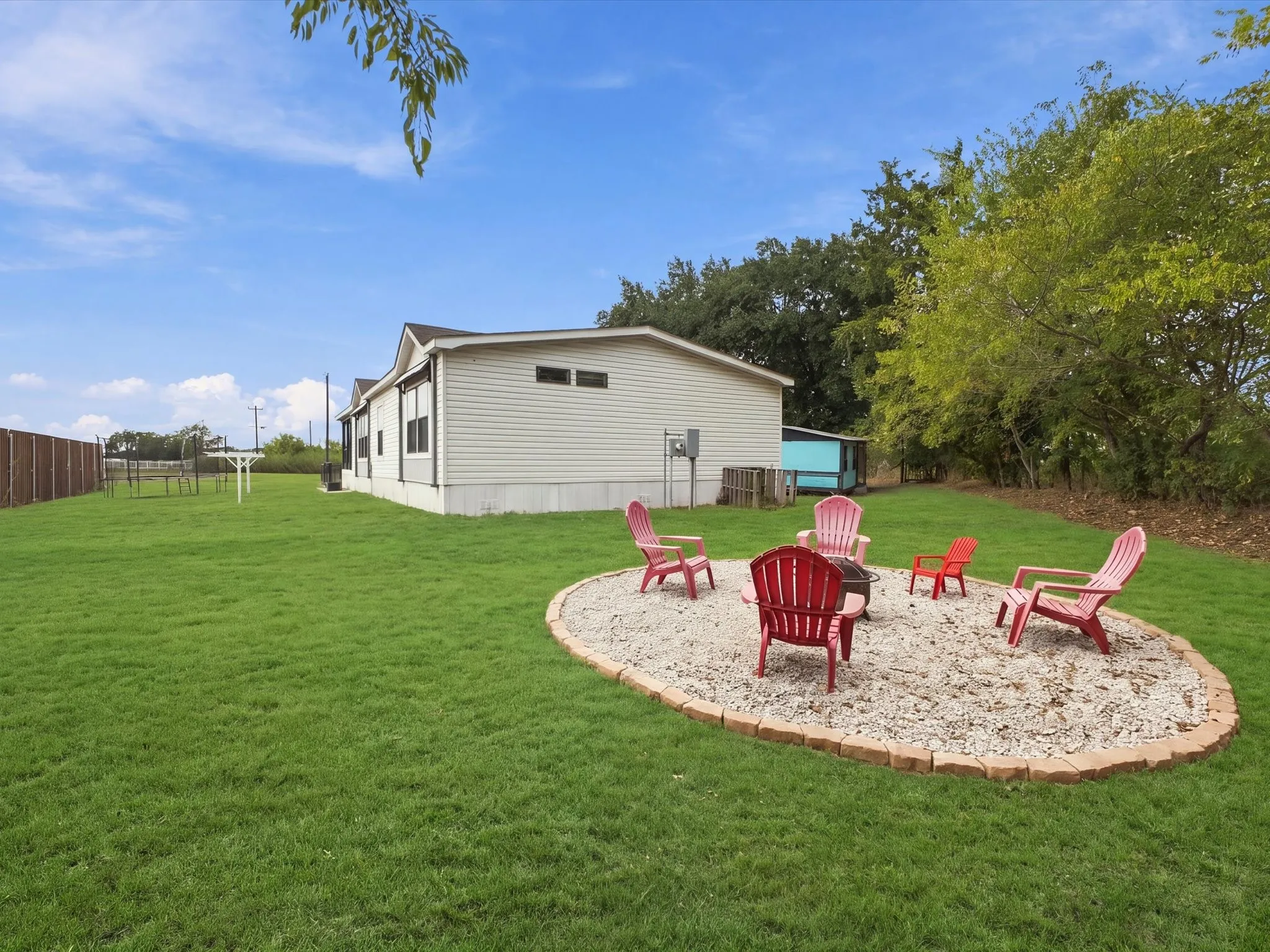 Expansive lawn area featuring a stone-edged fire pit