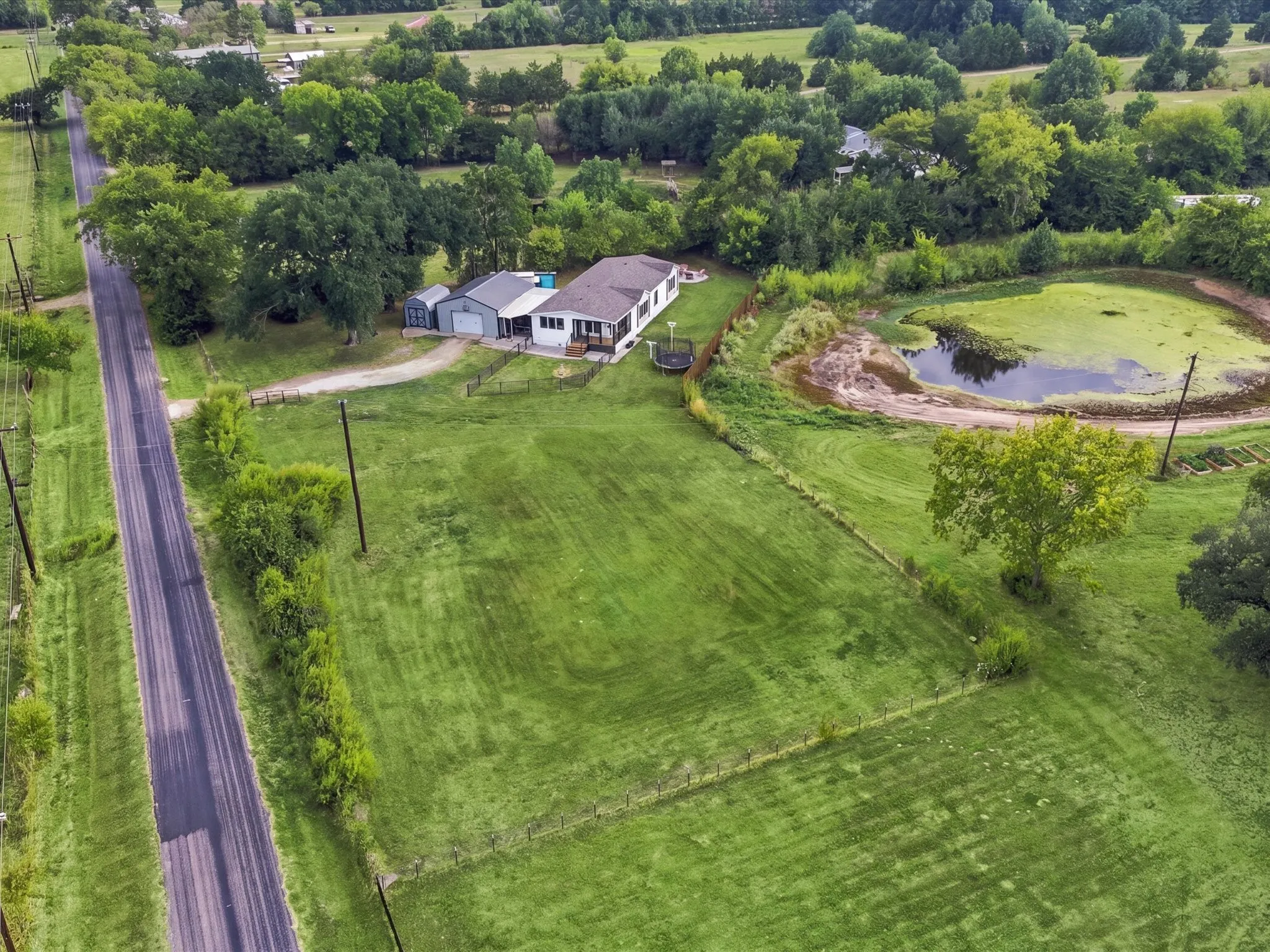 Expansive green acreage featuring a private pond, detached garage, and a long driveway