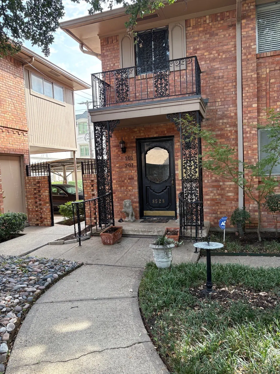 Brick exterior with a second-story balcony featuring decorative wrought iron railings