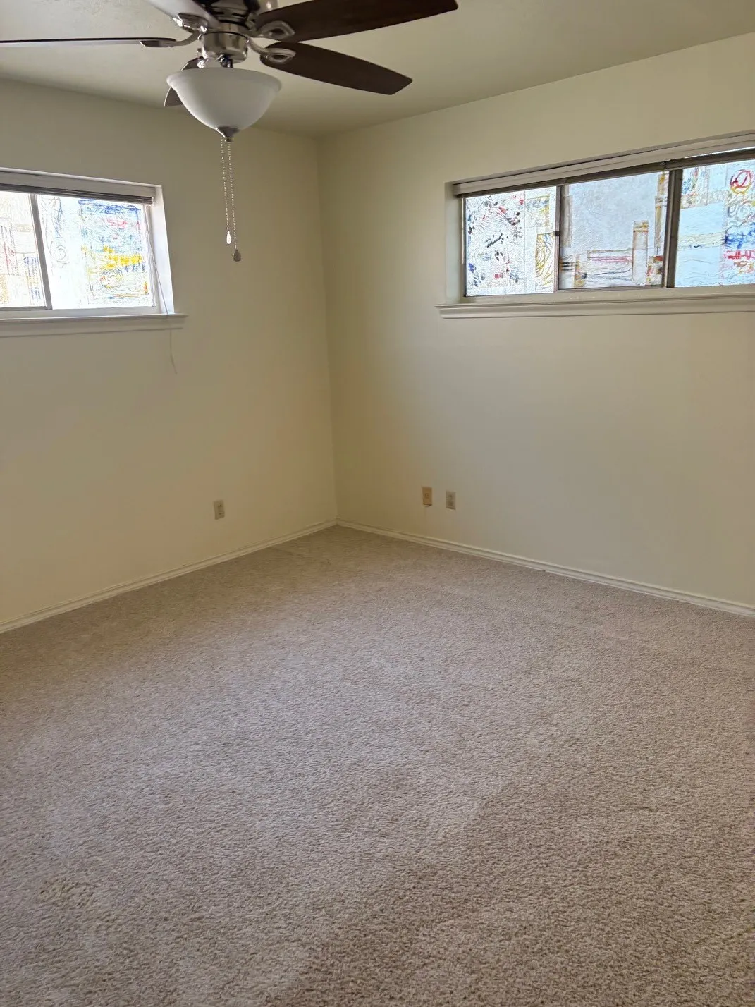 Neutral-toned carpeting, ceiling fan with integrated lighting, and two windows