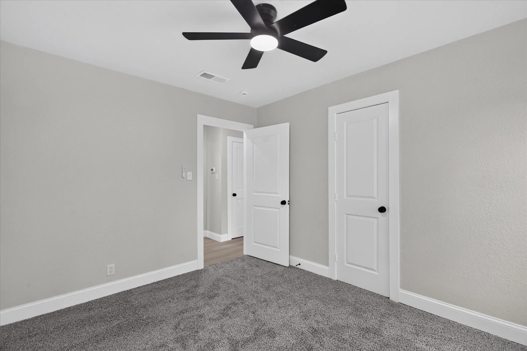 Carpeted flooring, ceiling fan with integrated lighting, white trim, and white doors with matte black hardware