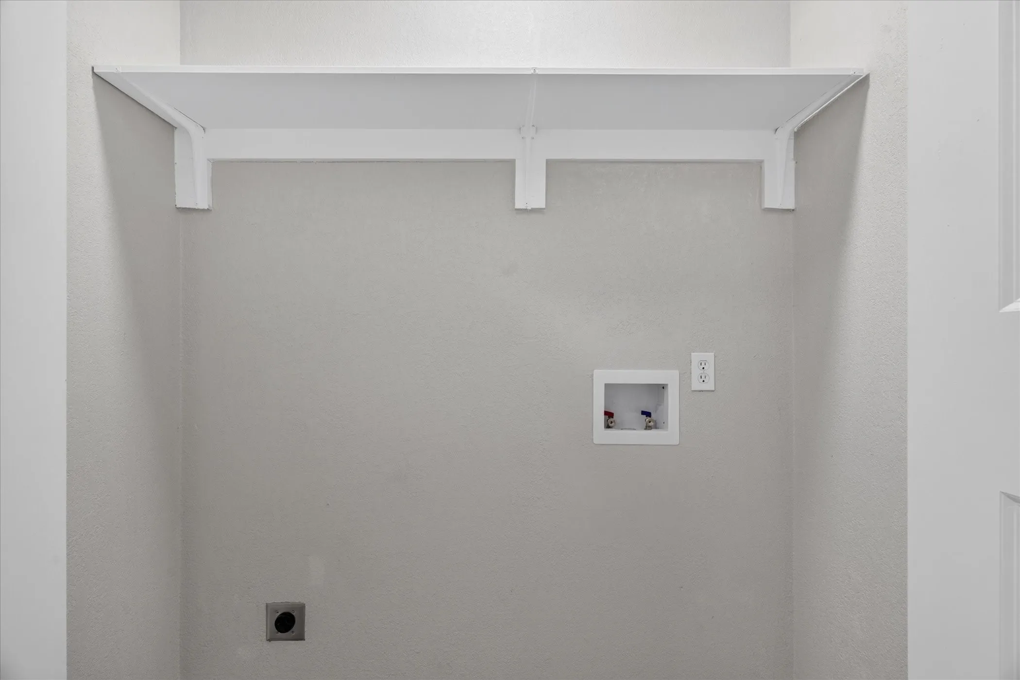 Integrated laundry utility connections, wall-mounted shelving, and neutral wall finish