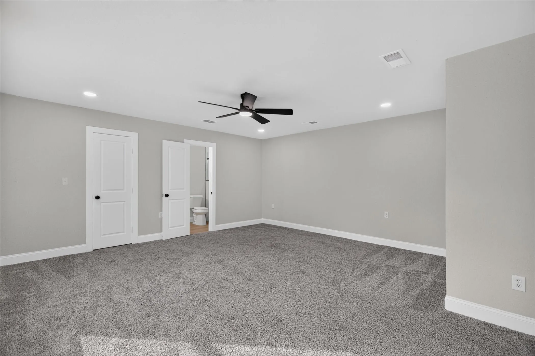 Spacious room featuring gray wall paint, gray carpeting, a ceiling fan, and recessed lighting