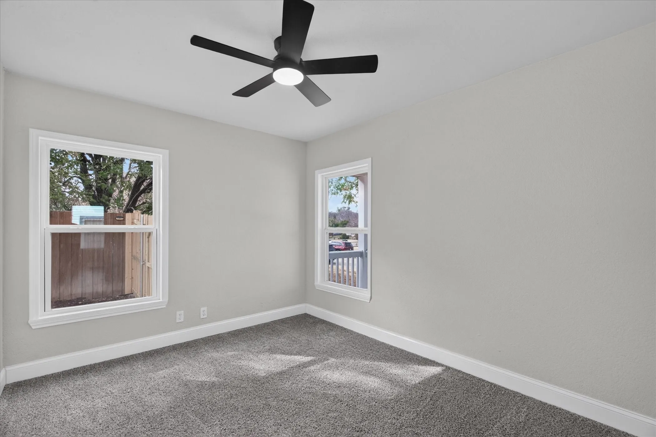 Neutral-toned walls, gray carpeting, white trim, and a black ceiling fan with integrated lighting