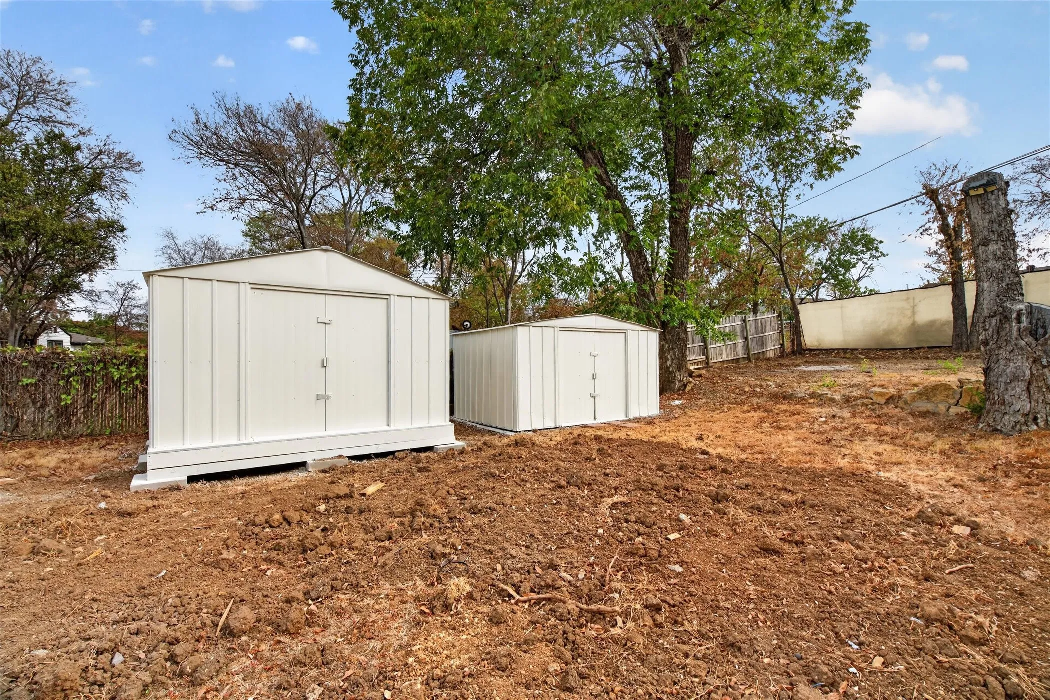 Two detached storage sheds with gable roofs, set on elevated platforms