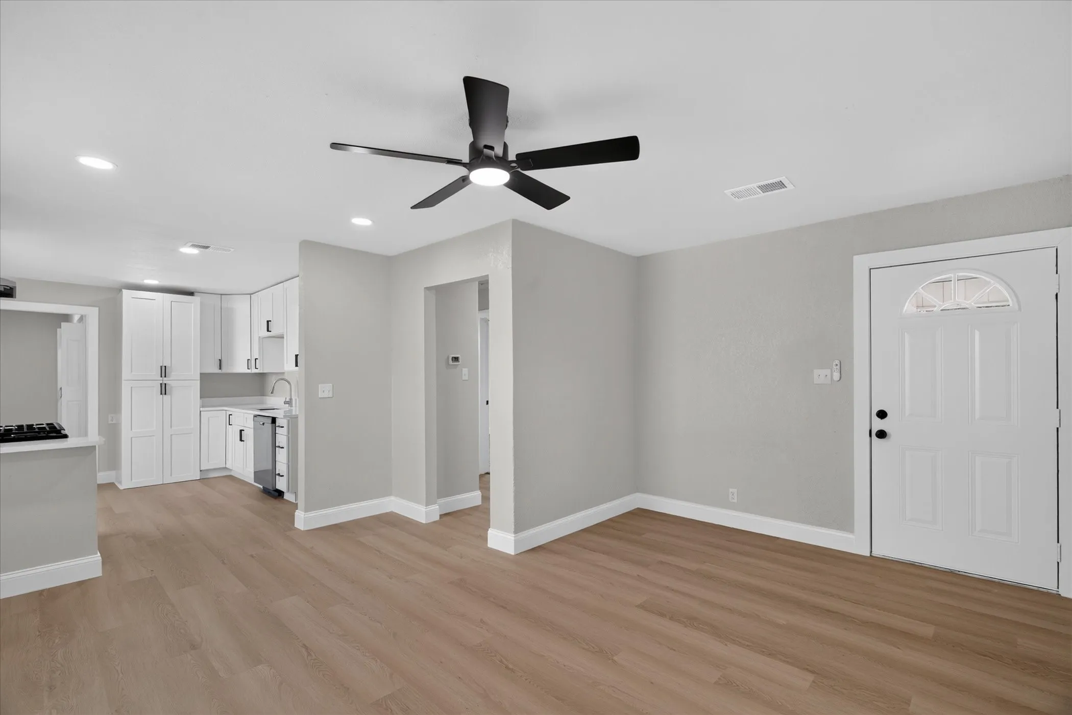 Open-concept living space with wood-finish flooring, recessed lighting, and a contemporary ceiling fan