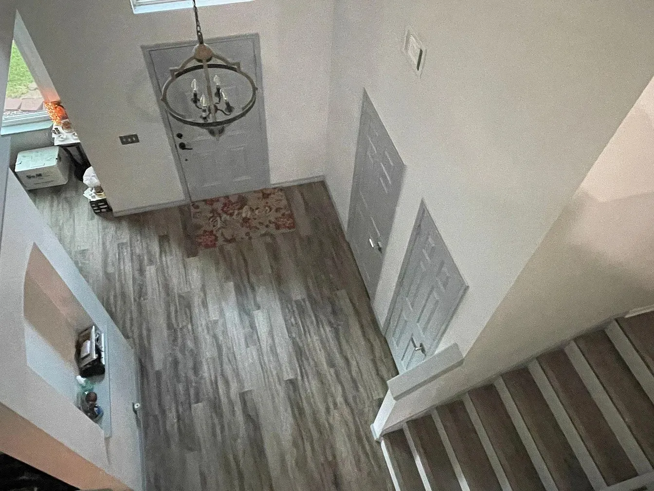 Two-story foyer with a chandelier, wood-finish flooring, and staircase with wood-finish treads