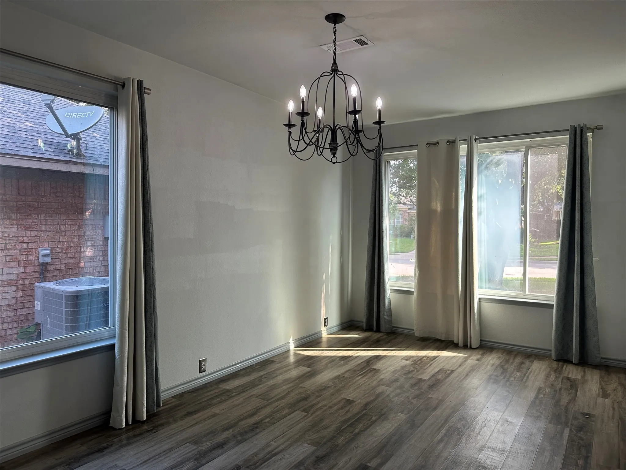 Wood-finish flooring with a matte finish, white walls, and a black wrought iron chandelier